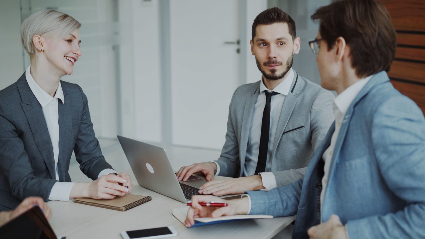 Business professionals discussing a plan around a laptop